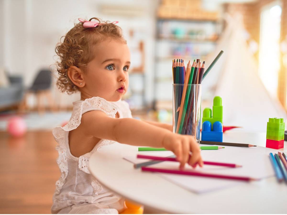 A little girl participating in daycare activities at a table with crayons and pencils in Highpoint.
