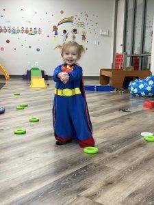 Birthday Parties - A little girl in a superman costume standing on the floor.